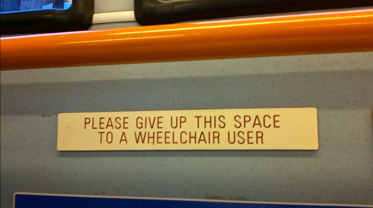 segno su un autobus che legge "please give up this space to a wheelchair user".