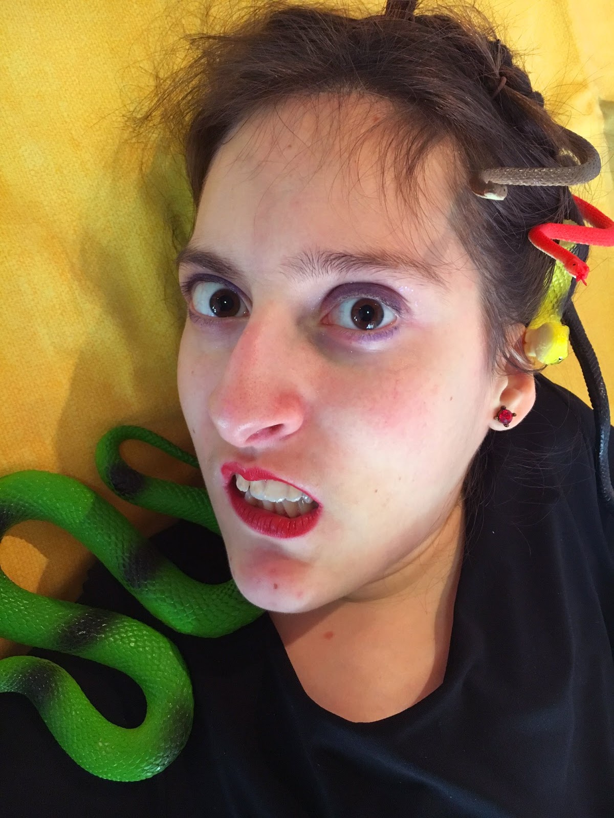primo piano di Elena vestita da Medusa, con i serpenti finti sulla testa e un'espressione sbigottita e infastidita