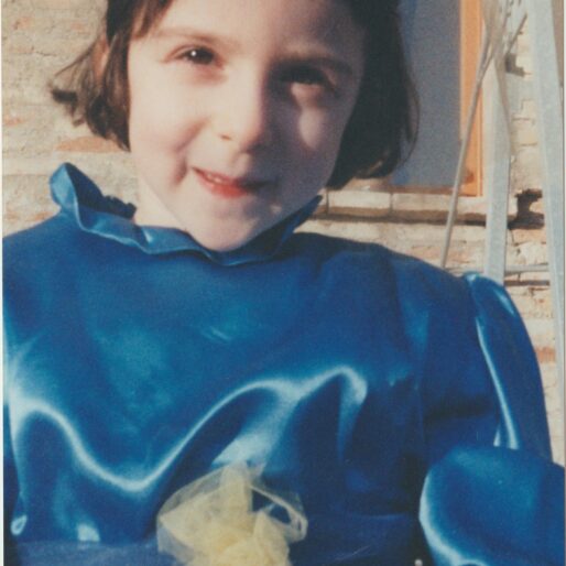 foto di Chiara a quattro anni. Ha i capelli neri corti e lisci, un vestito da fata blu e sorride