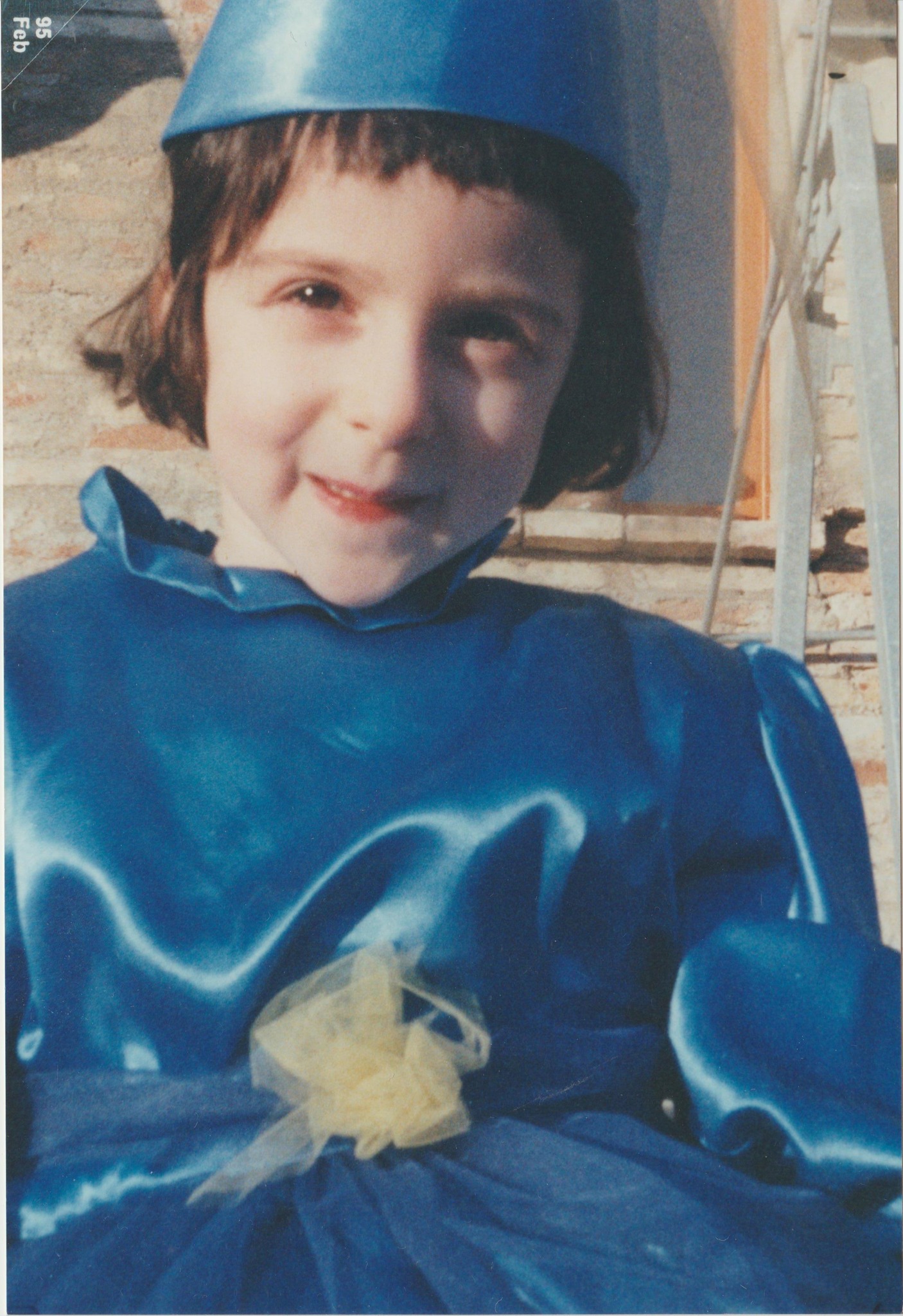 foto di Chiara a quattro anni. Ha i capelli neri corti e lisci, un vestito da fata blu e sorride